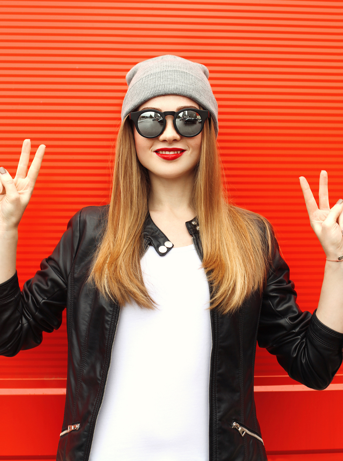 Eine selbstsichere junge Frau blickt cool in die Kamera und formt mit beiden Händen ein Peace-Zeichen, als Symbol für das Selbstbewusstsein und die innere Stärke, die der Kurs vermittelt.