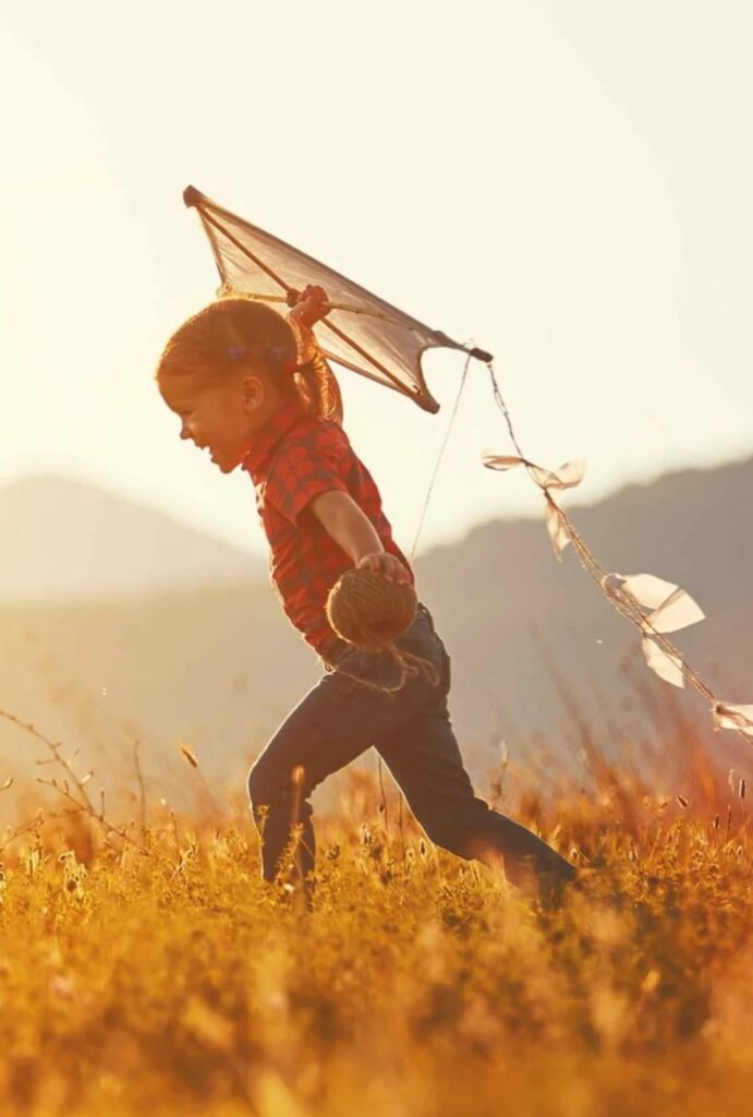 Kind mit Drachen im Sonnenlicht – Bild für Selbstvertrauen, Resilienz und emotionale Stärke im Coaching für Kinder und Jugendliche.